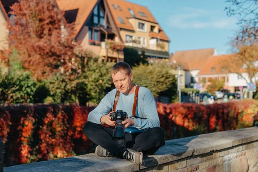 Man Sitting on Stairs in Old European City And Holding Photo Camera. Contemporary Stylish Blogger And Photographer