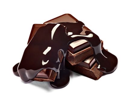 close up of chocolate pieces stack and chocolate syrup on white background