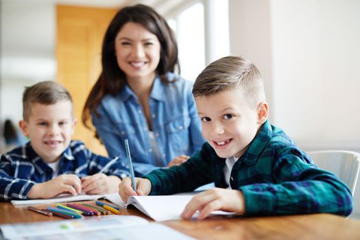 mother teaching sons and helping with homework at home, portrait of teenage boy