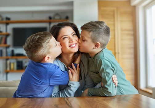 Shot of two adorable little boys affectionately kissing their mother at home