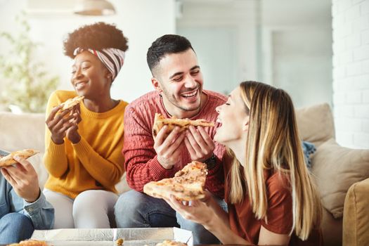young people friends having fun at the party, eating pizza