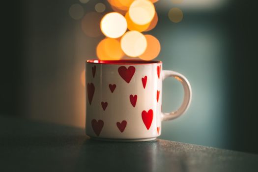 A cup of tea with or coffee with hearts on it is standing on table with bokeh on background. Saint Valentines day or love concept. High quality photo