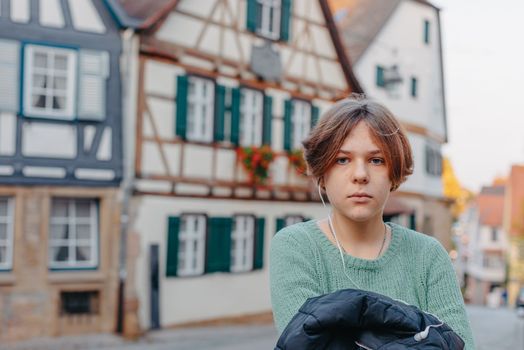 A Beautiful Girl Stands Against The Background Of The Window Of An Old European House. Tourism & Travel Concept. Nice Portrait Of A Young Woman, In Boho Style Outdoors In Fall Autumn Day. Caucasian Female Girl 12 Years Old.