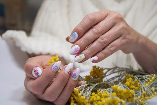 hands with a beautiful multi-colored manicure hold a bouquet of yellow flowers. High quality photo