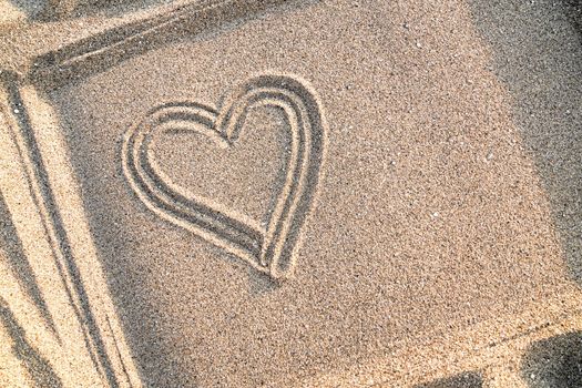 Background with painted heart on sand, concept of love, top view, copy space