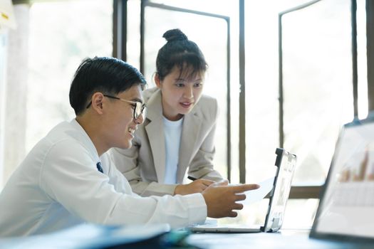 Businesspeople or colleagues are working together on investment project, discussing, sharing ideas, planning, and analyzing the business strategy and finance using laptop computer.