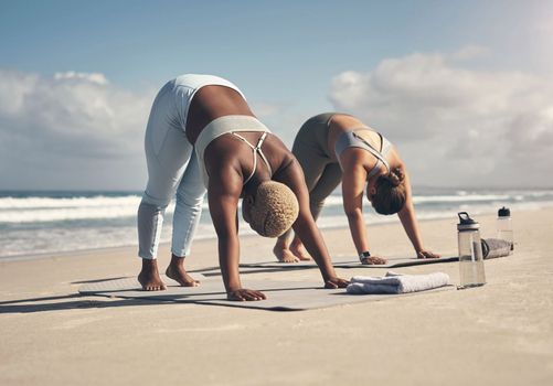 Yoga works a variety of muscles. two young women practicing yoga on the beach