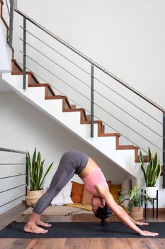 Young asian woman doing downward facing dog at home living room. Vertical image. Copy space. Healthy lifestyle.