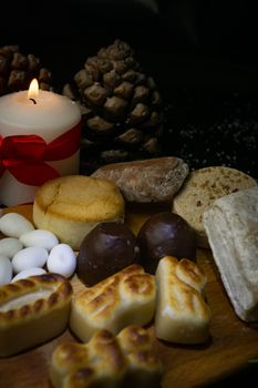 typical christmas sweets on the table decorated with pine cones, pine branches and coloured candles.