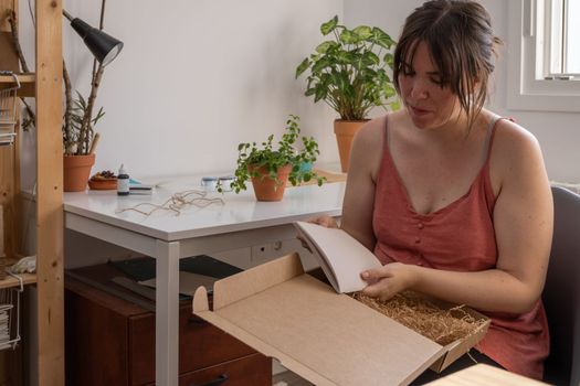 young girl opening a handmade eco-friendly gift wrapped in a cardboard box in her home