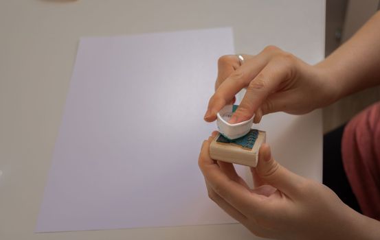 woman's hands placing a sustainable packaging stamp on a blank sheet of paper