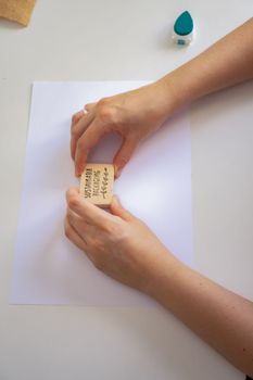 woman's hands placing a sustainable packaging stamp on a blank sheet of paper