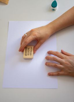 woman's hands placing a sustainable packaging stamp on a blank sheet of paper