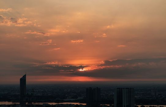 Bangkok, Thailand - Jan 25, 2022 : Gorgeous panorama scenic of the sunrise or sunset with cloud on the orange sky over large metropolitan city in Bangkok. Copy space, No focus, specifically.