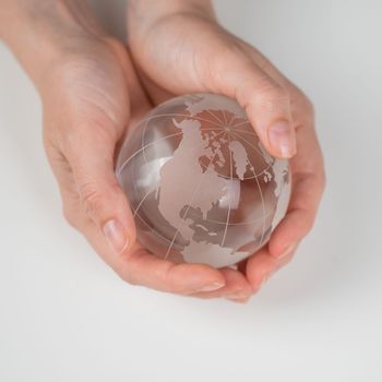 Crystal globe in female hands on a white background