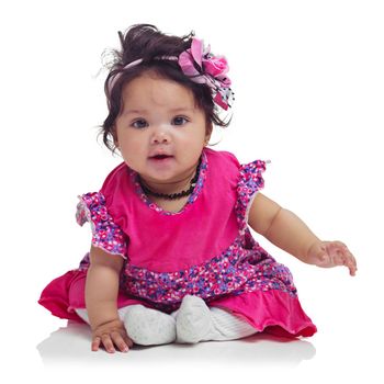 Cute, happy and portrait of a baby girl sitting isolated on a white background in a studio. Girly, playful and innocent, adorable and small child smiling with happiness on a studio background.