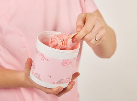 Woman holding sugar paste for hair removal. Depilation in a beauty salon.