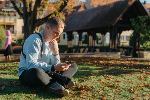 Professional photographer taking picture of beautiful autumn park. man professional photographer sit with camera in autumn park