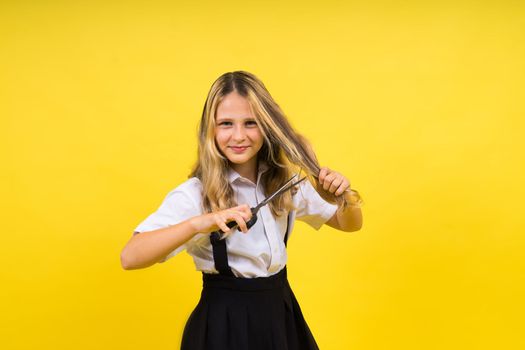 Teenage school girl with scissors, isolated on yellow background. Child creativity, art and crafts.