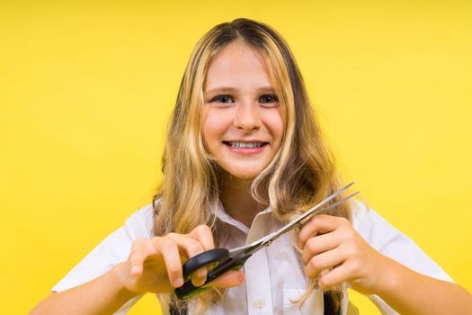 Teenage school girl with scissors, isolated on yellow background. Child creativity, art and crafts.