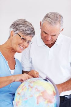 Couple searching travel destination on globe. Happy mature couple planning vacation while looking at globe
