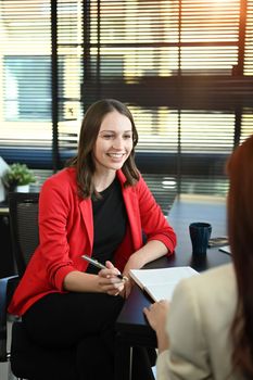 Smiling caucasian female HR manager interviewing candidate female in seating area of modern office.