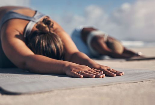 Yoga helps you to slow down. two young women practicing yoga on the beach