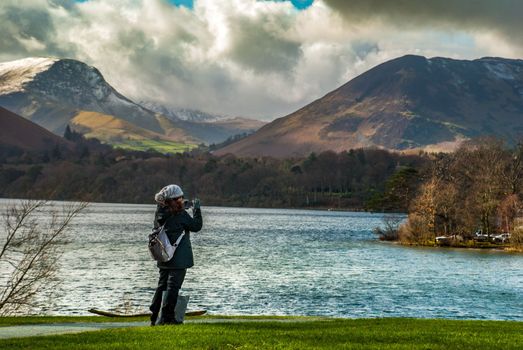 Lake District, UK - apr 15, 2019 : A woman who is taking pictures of the scenery of the lake and the mountains in the Lake District area.