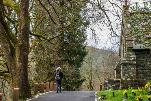 Lake District, UK - apr 15, 2019 : Women who visit the beautiful old stone church on the mountain