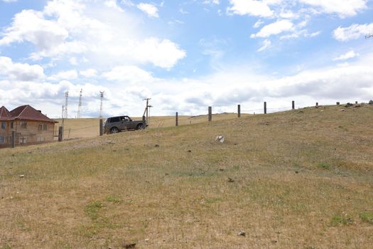 The car goes uphill along the old fence and the blue sky on olkhon island