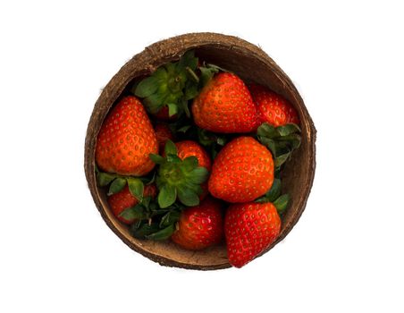 Fresh strawberries in a coconut shell on white background.