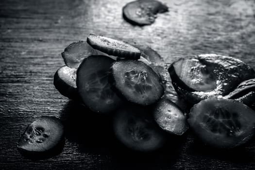 Close-up of ingredients of facial or face pack or face mask on a wooden surface i.e. slices of cucumber and Aloe Vera in dark Gothic colors for brightening and softening the skin.