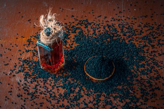AYURVEDIC HERB i.e. Kalonji,black caraway seeds with its beneficial and essential oil on a brown surface in dark Gothic colors.This oil is used in weight loss,lowing the blood sugar/diabetes etc.