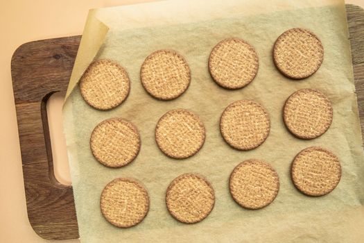 Freshly baked homemade sesame seed cookies on wooden board, rustic table. Healthy, tasty snack, honey seed bar, round form biscuits. Organic dessert, top view in row vegan