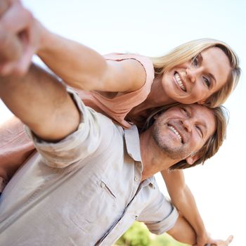 Only this kind of freedom can be found in nature. a happy mature enjoying a piggyback ride outdoors