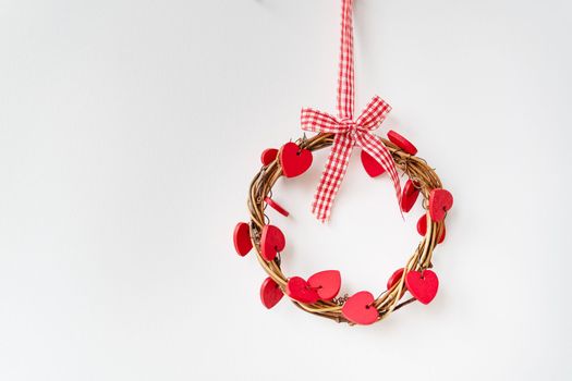 A decorative ring with wooden red hearts hangs on the wall. The concept of holiday, love, St. Valentine's Day