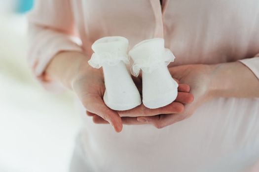 baby clothes for a newborn girl slippers in the hands of mom