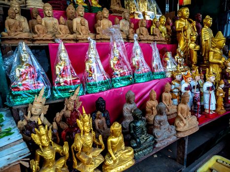 Wood products carved in the form of Buddha and deities in Burmese art that are sold by the entrance of a temple in Burma