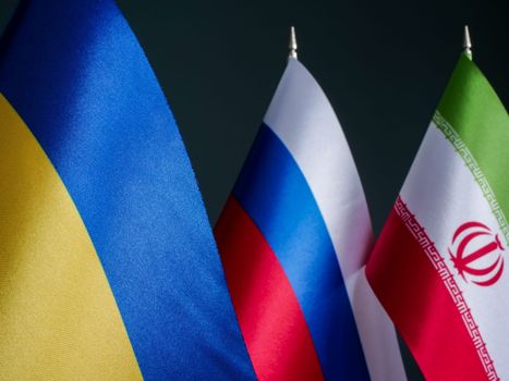 Flag of Ukraine in front of flags of Russia and Iran as allies.