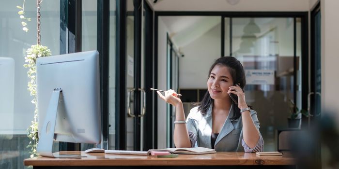 Asian Business woman working to analyze technical price graph and indicator with business team talking by cell phone. account or saving money or insurance concept