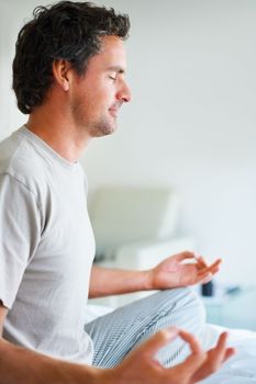 Yoga on bed. Side view of mature man sitting on bed and doing yoga