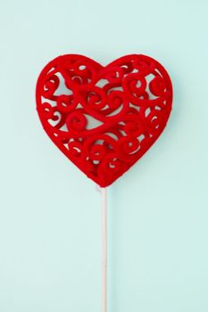 Decorative red gift heart on a stick on a light blue background. Valentine's Day concept. Copy space.