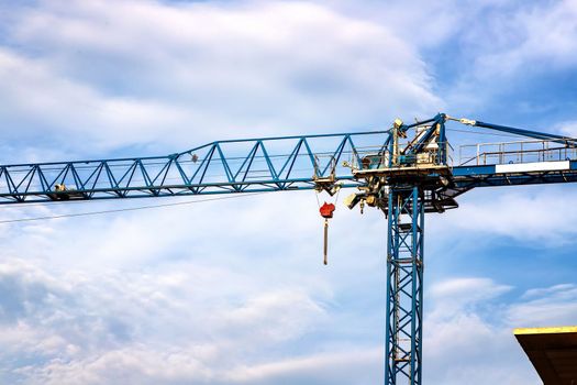 Construction tower crane against a blue sky with clouds.