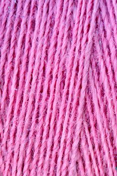 The macro texture of pink cotton thread on bobbin, close-up, copy space.