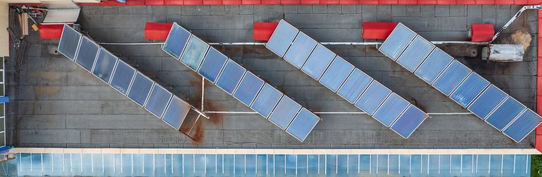 Solar water heaters are installed on the tile roof of the hotel for eco heating of water. Banner view