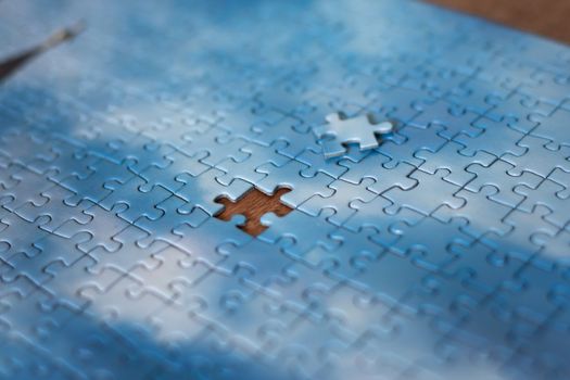 The missing piece of the sky puzzle, the concept of completing a big job, the final of the project, the successful solution of business problems. The hand puts the last piece of the jigsaw