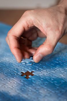 The missing piece of the sky puzzle, the concept of completing a big job, the final of the project, the successful solution of business problems. The hand puts the last piece of the jigsaw