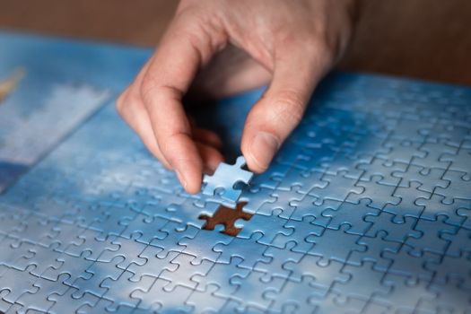 The missing piece of the sky puzzle, the concept of completing a big job, the final of the project, the successful solution of business problems. The hand puts the last piece of the jigsaw