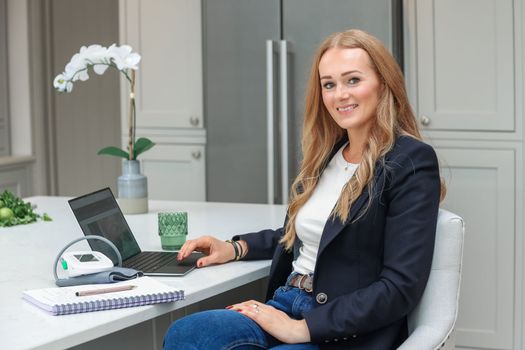 Remote Work. Beautiful middle age Freelancer Lady Working With Laptop In Kitchen, Happy Woman Using Computer At Home, Sitting At Table In Cozy Interior, Enjoying Online Job, Free Space