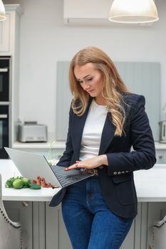 Remote Work. Beautiful middle age Freelancer Lady Working With Laptop In Kitchen, Happy Woman Using Computer At Home, Sitting At Table In Cozy Interior, Enjoying Online Job, Free Space